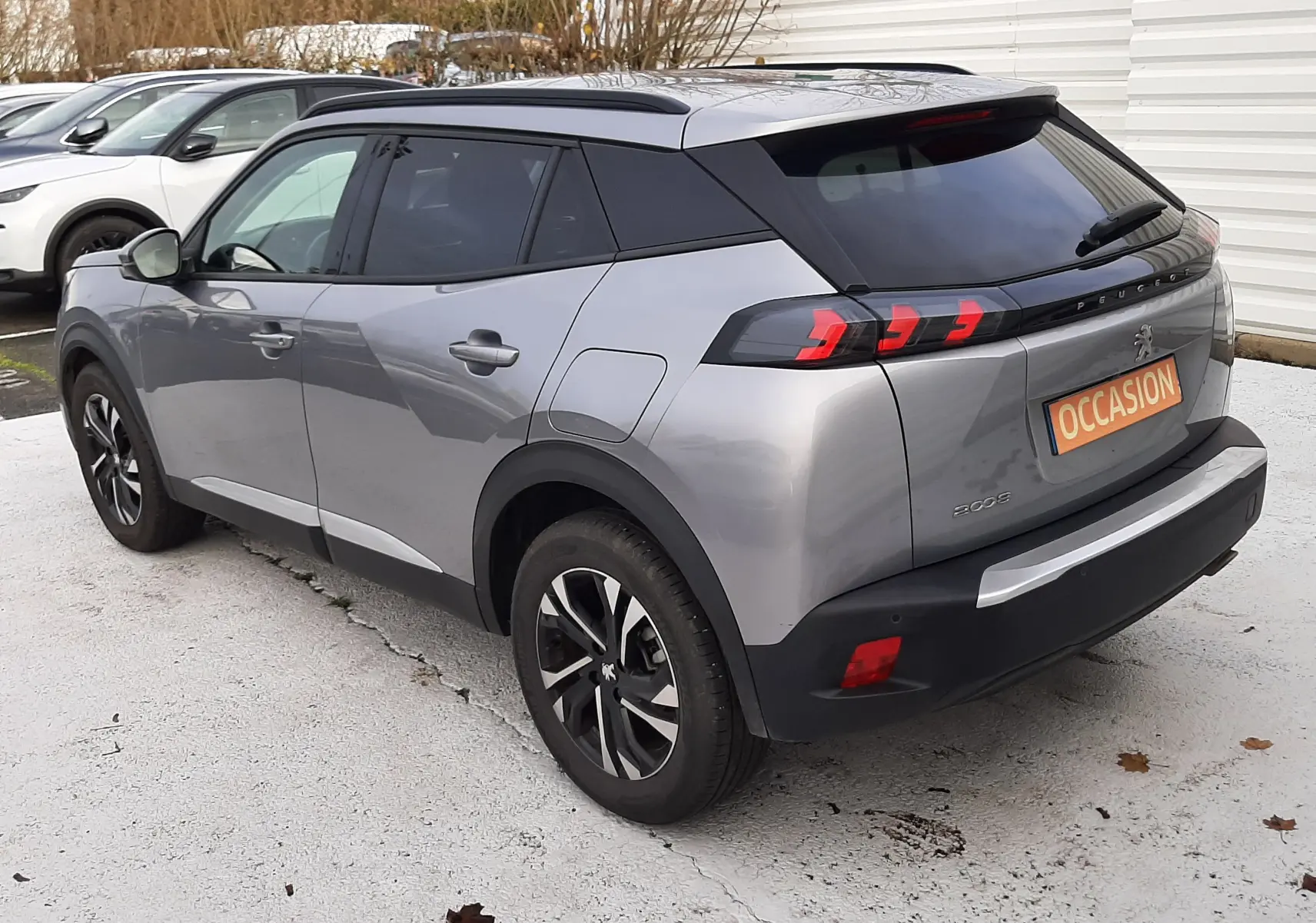 Peugeot 2008 gris vue 3/4 arrière droit, avec feux arrière à LED et toit noir contrasté.