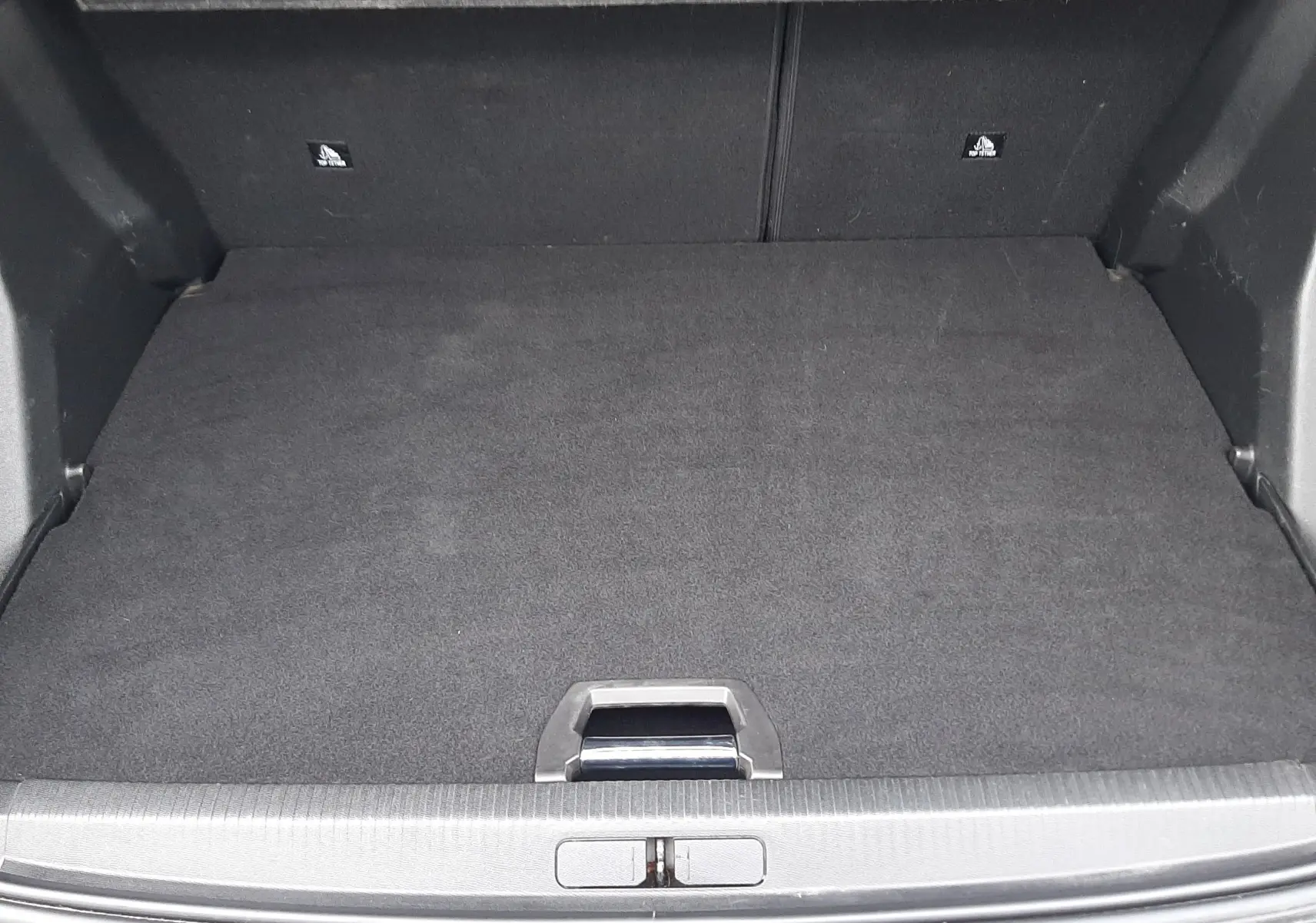 Coffre ouvert vu de l'arrière d'un Peugeot 2008 gris, montrant un espace de chargement propre et bien fini.