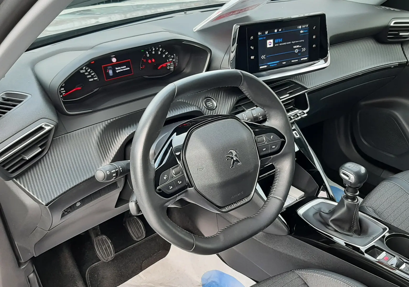 Vue intérieure côté conducteur du Peugeot 2008 gris 2021, avec volant compact, tableau de bord numérique et levier de vitesses manuel.