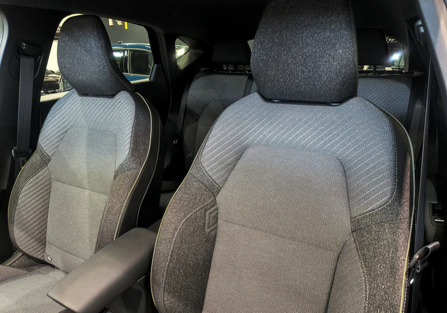 Gros plan sur les sièges avant en tissu gris et noir du Renault Captur Mild Hybrid 2025, intérieur spacieux et moderne.