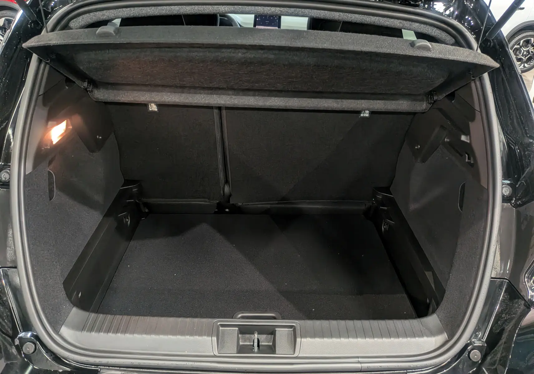 Coffre ouvert du Renault Captur noir Mild Hybrid 2025, vue arrière montrant l'espace de chargement vide et la lumière intérieure allumée.