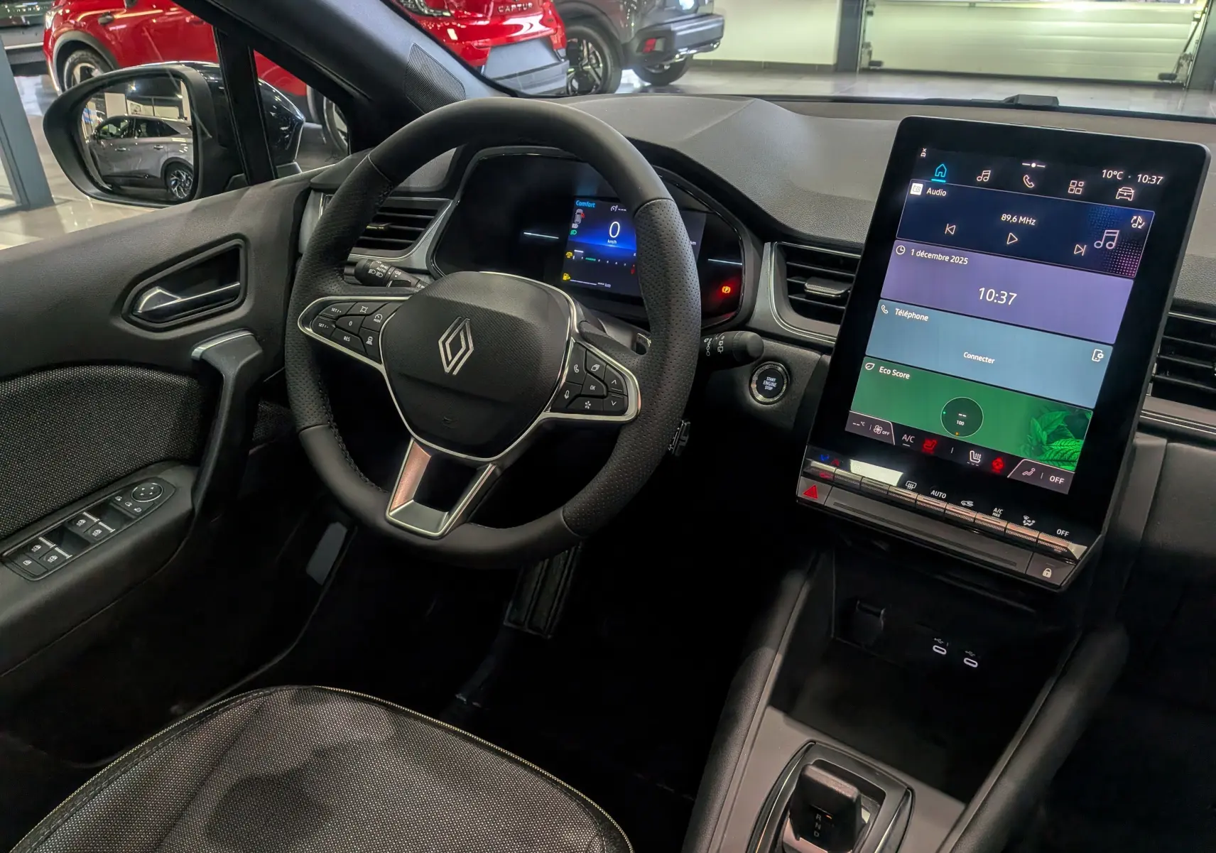 Vue intérieure côté conducteur du Renault Captur 2025 noir, avec volant multifonction et écran tactile vertical lumineux.