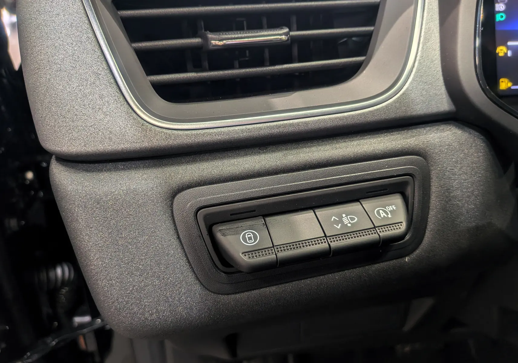 Gros plan sur les commandes d'éclairage et de verrouillage à gauche du tableau de bord du Renault Captur noir Mild Hybrid 2025.