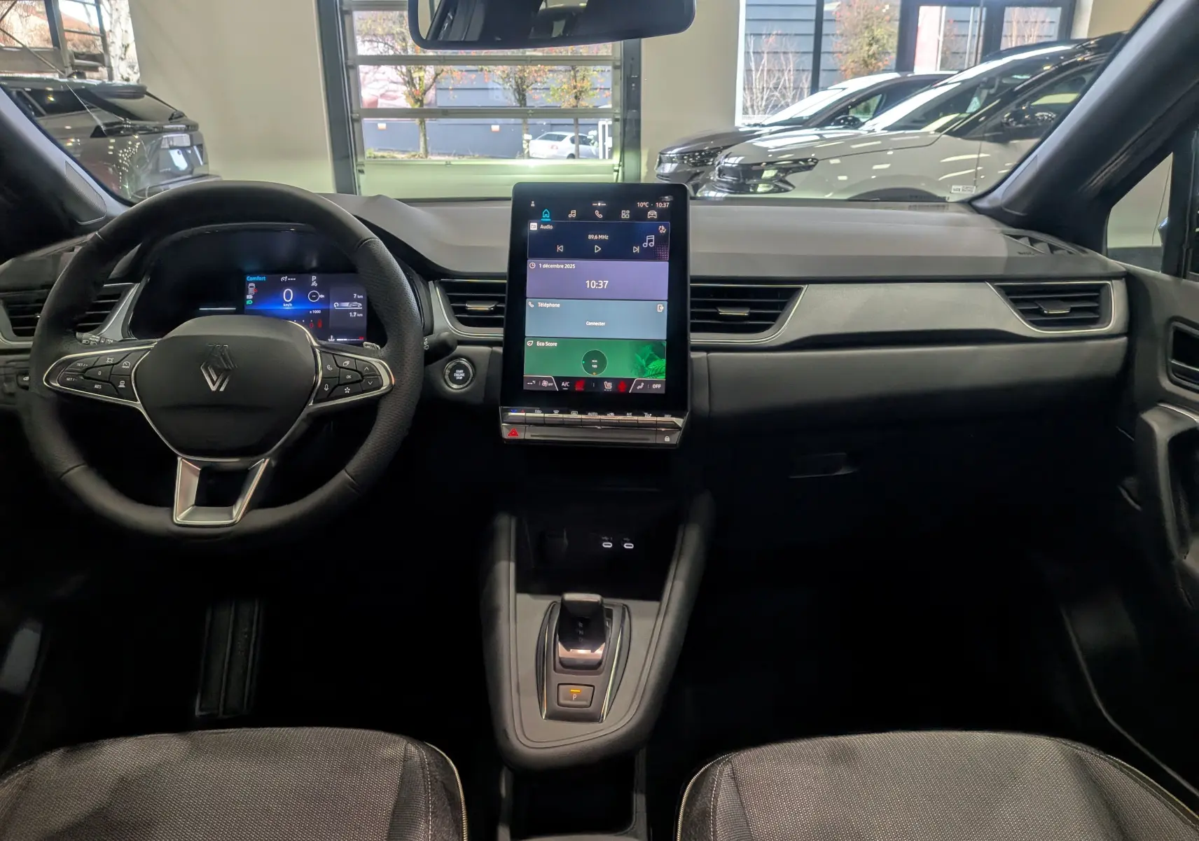 Intérieur du Renault Captur 2025 noir, vue frontale du tableau de bord avec écran tactile vertical et volant multifonction.