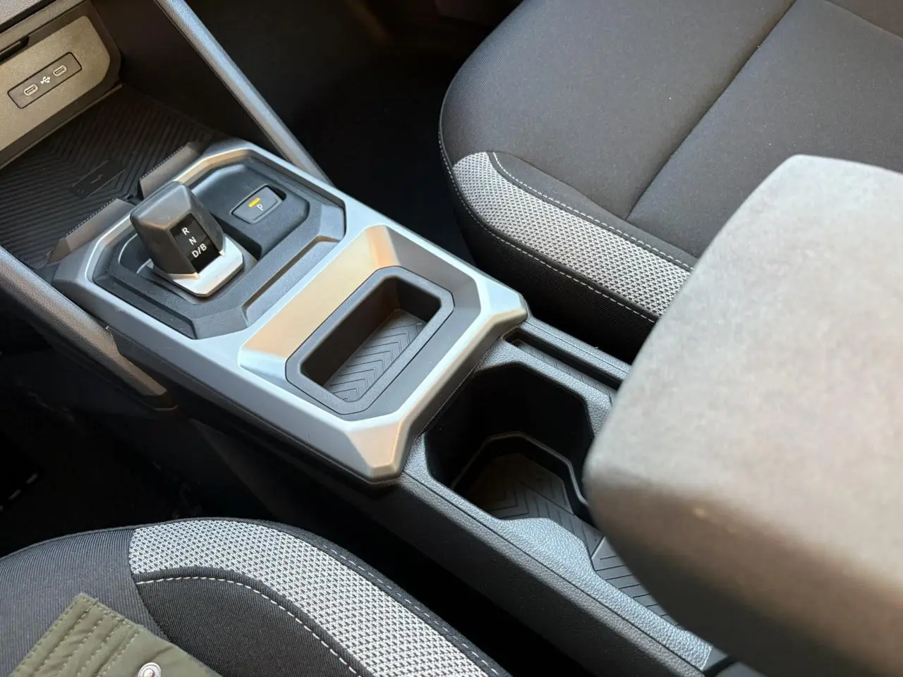 Vue rapprochée de la console centrale du Dacia Duster blanc Glacier, avec levier de vitesses automatique et porte-gobelets.