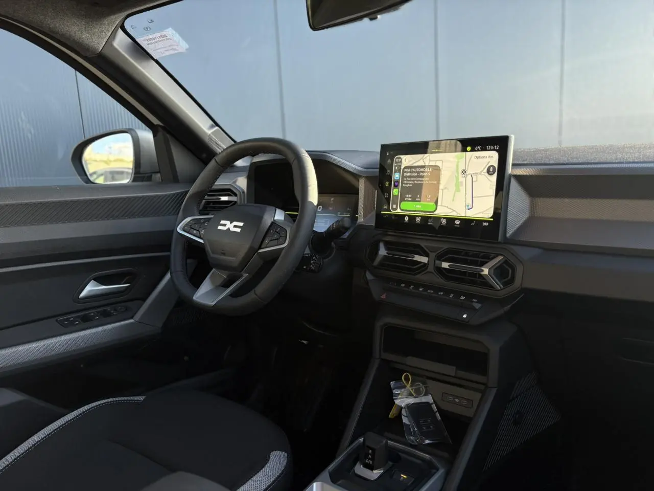 Vue intérieure côté conducteur du Dacia Duster 2026 avec tableau de bord digital et écran tactile central.