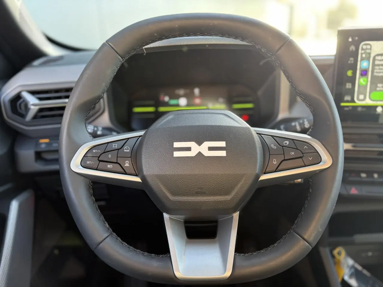 Volant noir avec commandes intégrées, vue frontale du poste de conduite du Dacia Duster 2026 blanc Glacier.