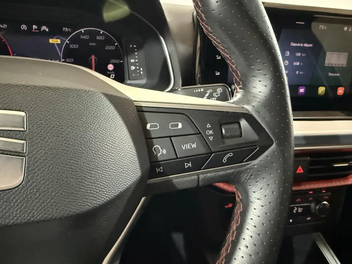 Gros plan sur le volant cuir et alu de la SEAT IBIZA 1.0 TSI 110 FR 2024, avec commandes multifonctions et tableau de bord numérique.