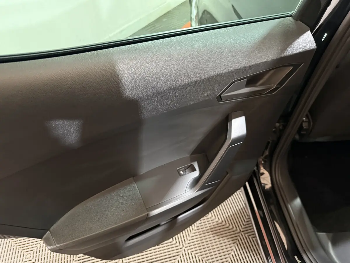 Vue rapprochée de la porte arrière droite noire d'une SEAT Ibiza 2024, avec poignée et commande de vitre électrique.