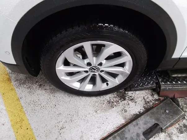 Gros plan sur la roue avant droite d’un Volkswagen T-Roc blanc toit noir, jante alliage 17 pouces en stationnement.