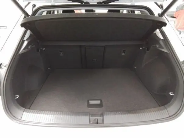 Coffre ouvert vu de l'arrière d'un Volkswagen T-Roc blanc toit noir, montrant un espace de chargement vide et spacieux.