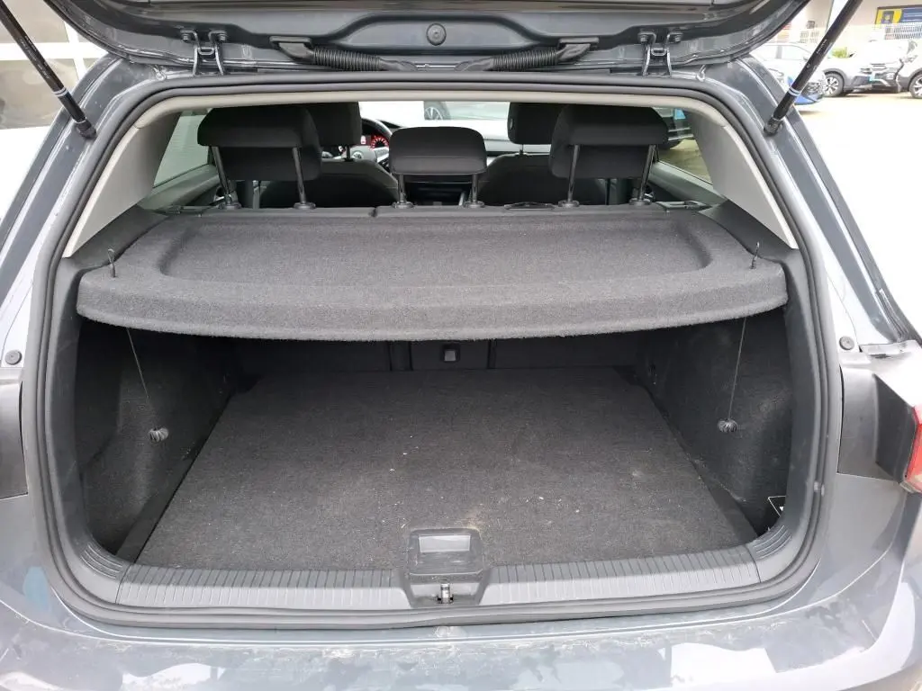 Vue arrière du coffre ouvert d'une Volkswagen Golf gris 2022, avec cache-bagages et intérieur noir visible.