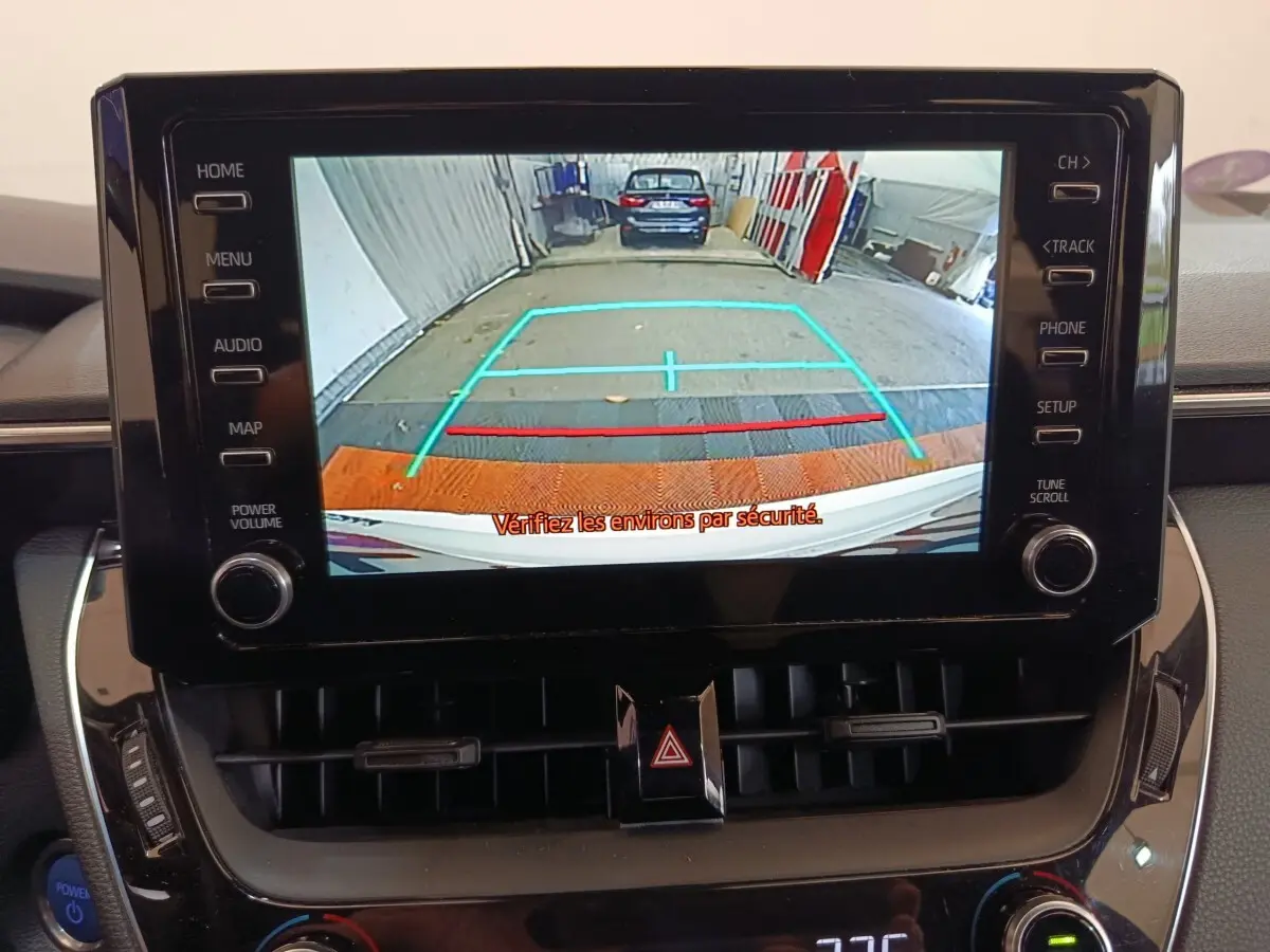 Vue de l'écran central de la Toyota Corolla Hybride blanche 2020 montrant la caméra de recul avec repères colorés.