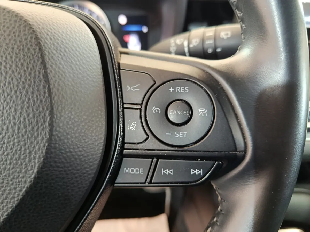 Gros plan sur les commandes multifonctions à droite du volant cuir noir de la Toyota Corolla Hybride 122h Active.