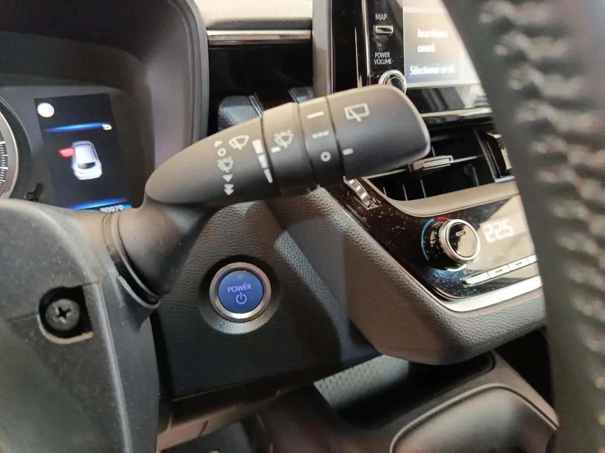 Détail intérieur du tableau de bord de la Toyota Corolla Hybride 122h 2020 avec bouton démarrage bleu et commandes de climatisation.