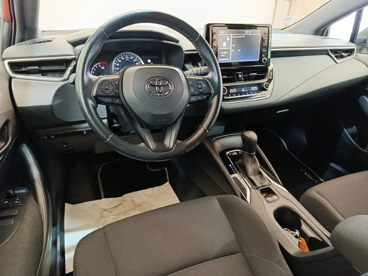 Vue intérieure avant de la Toyota Corolla Hybride 122h Active 2020, volant cuir multifonctions et écran tactile central.