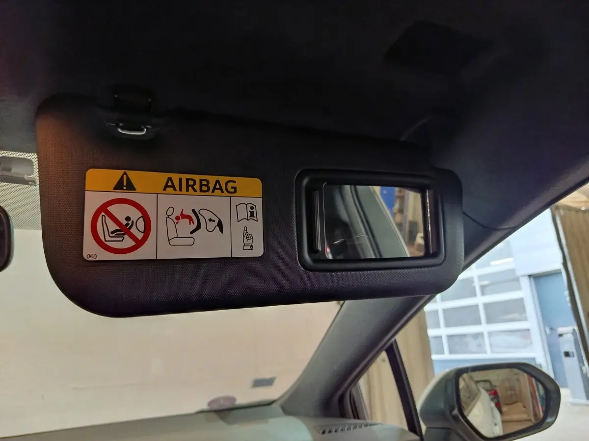 Détail du pare-soleil côté conducteur avec miroir et étiquette airbag dans une Toyota Corolla blanche 2020.