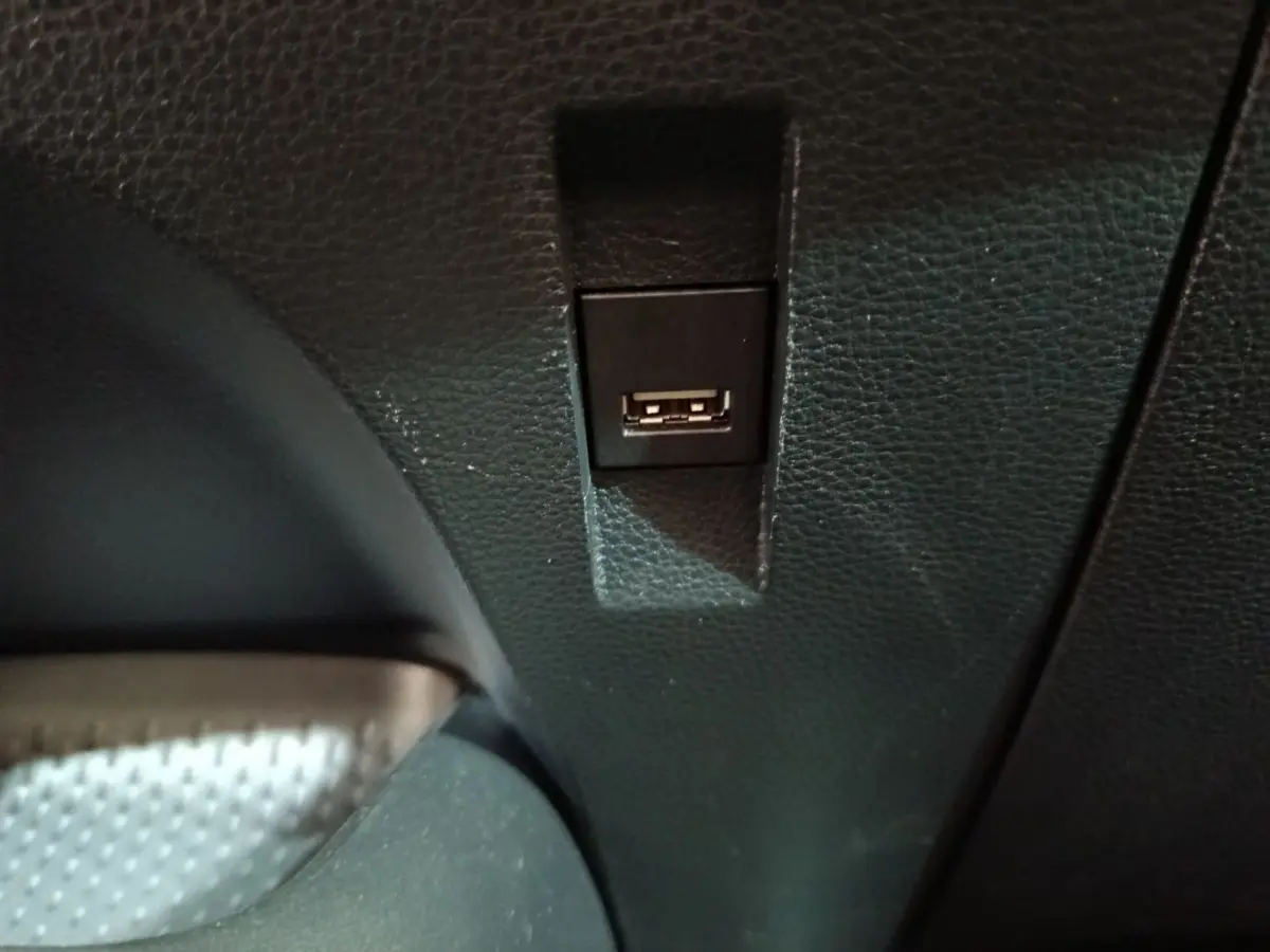 Prise USB noire intégrée dans la console intérieure d'une Toyota Corolla Hybride blanche, vue rapprochée.