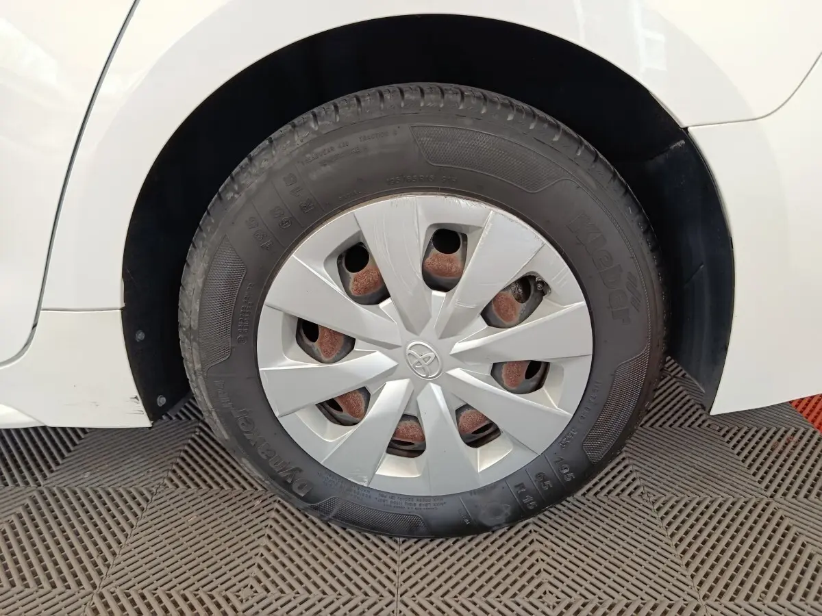 Gros plan sur la roue arrière droite blanche d'une Toyota Corolla Hybride 122h Active avec enjoliveur gris et jante visible.