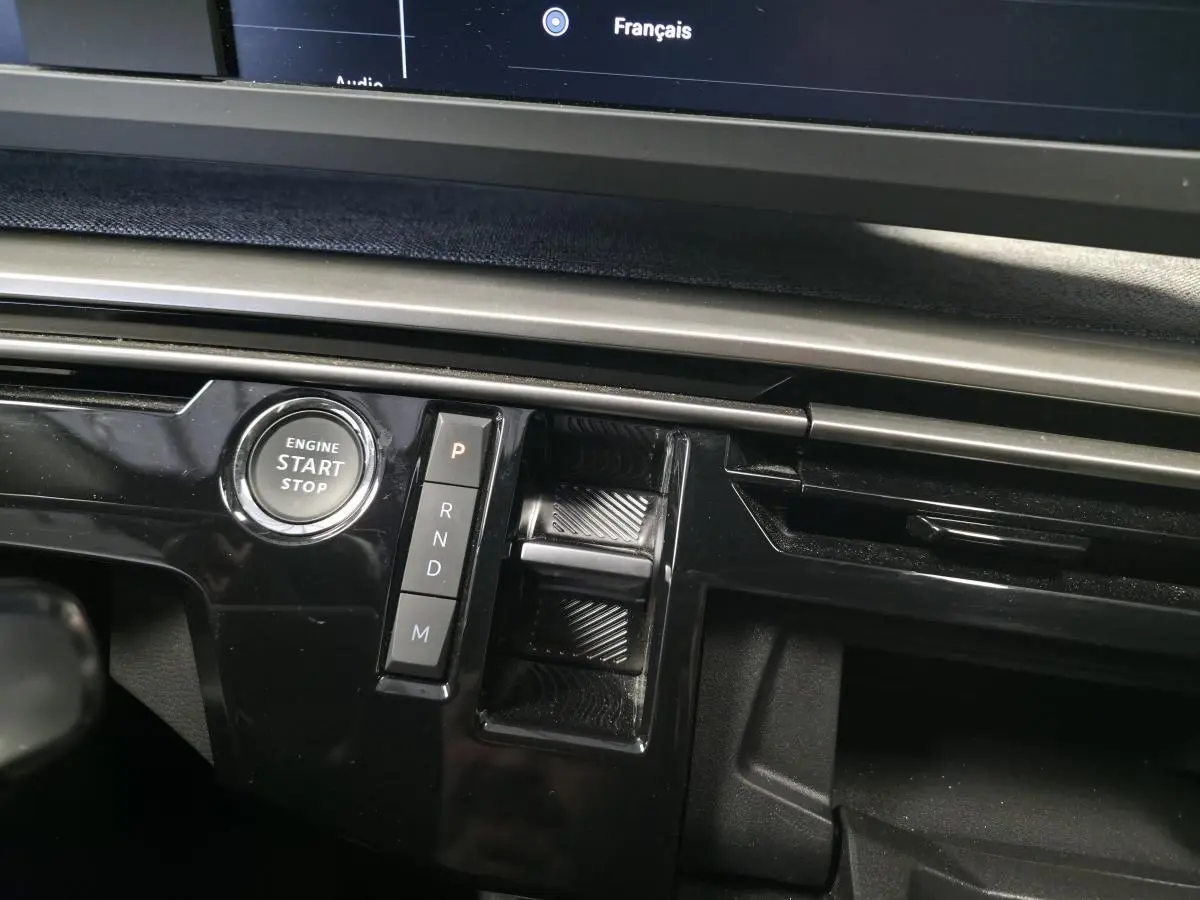 Gros plan sur la console centrale noire laquée du Peugeot 3008 Hybrid 2025 avec bouton start/stop et commandes de boîte auto.