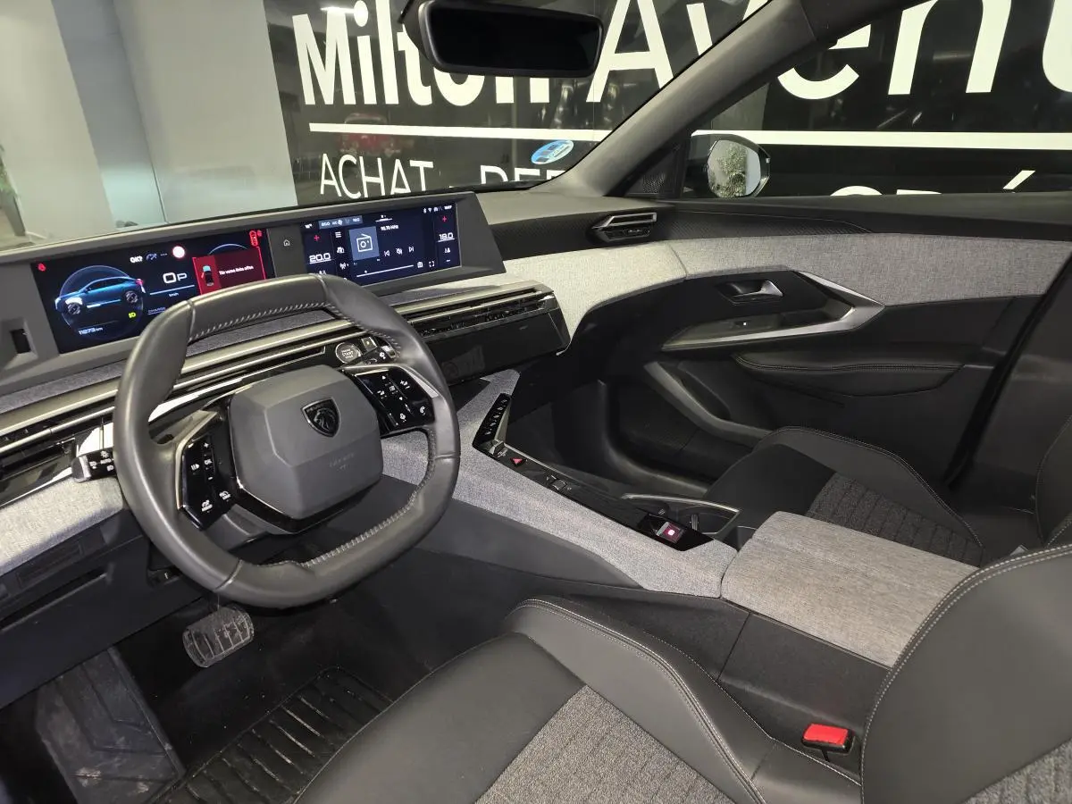 Intérieur du Peugeot 3008 noir hybride, vue côté conducteur, tableau de bord numérique et sellerie tissu gris et noir.