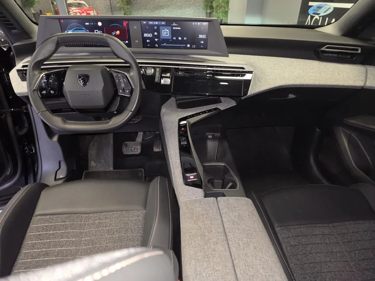 Vue intérieure avant du Peugeot 3008 2025 noir, avec tableau de bord numérique et console centrale en tissu gris.