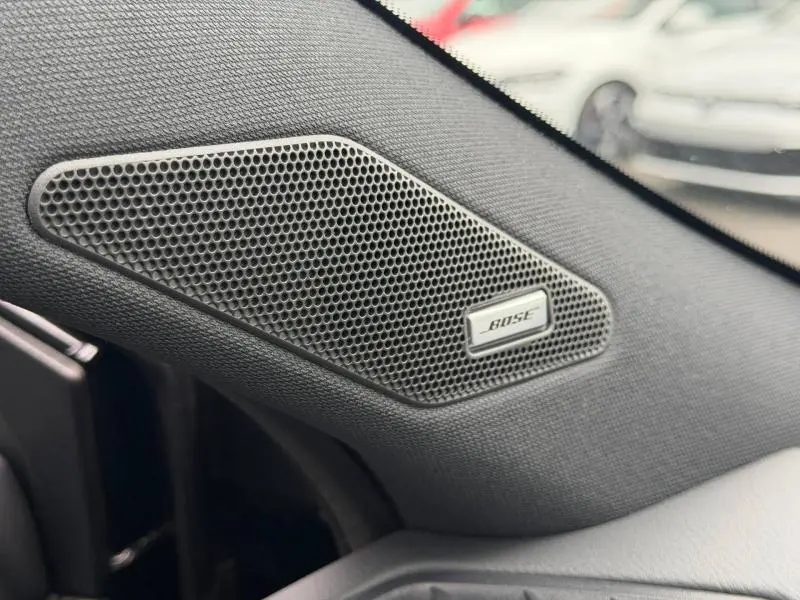 Gros plan sur l'enceinte Bose intégrée côté gauche dans l'habitacle noir du Nissan Qashqai 2024 Tekna+