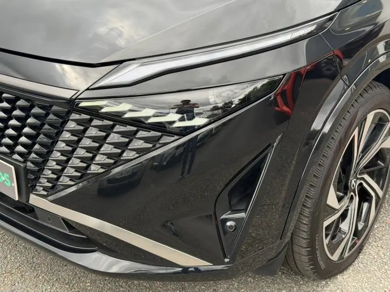 Gros plan sur l'avant droit noir Kuro métallisé du Nissan Qashqai 2024, avec phares LED et calandre distinctive.