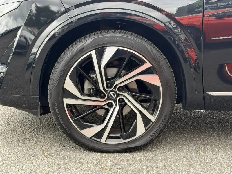 Gros plan sur la roue avant droite du Nissan Qashqai 2024 noir Kuro métallisé avec jante alu bicolore moderne.