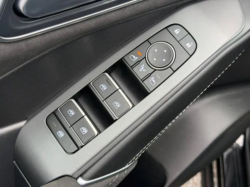Gros plan sur les commandes de lève-vitres et réglages des rétroviseurs côté conducteur du Nissan Qashqai 2024 noir Kuro.