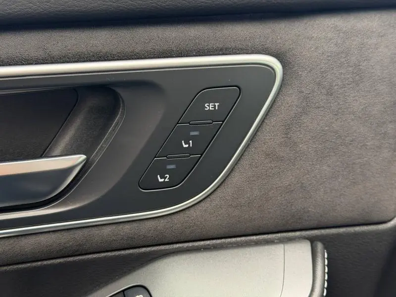 Détail du panneau de porte intérieur noir Kuro du Nissan Qashqai 2024 avec commandes mémoire des sièges et poignée argentée.