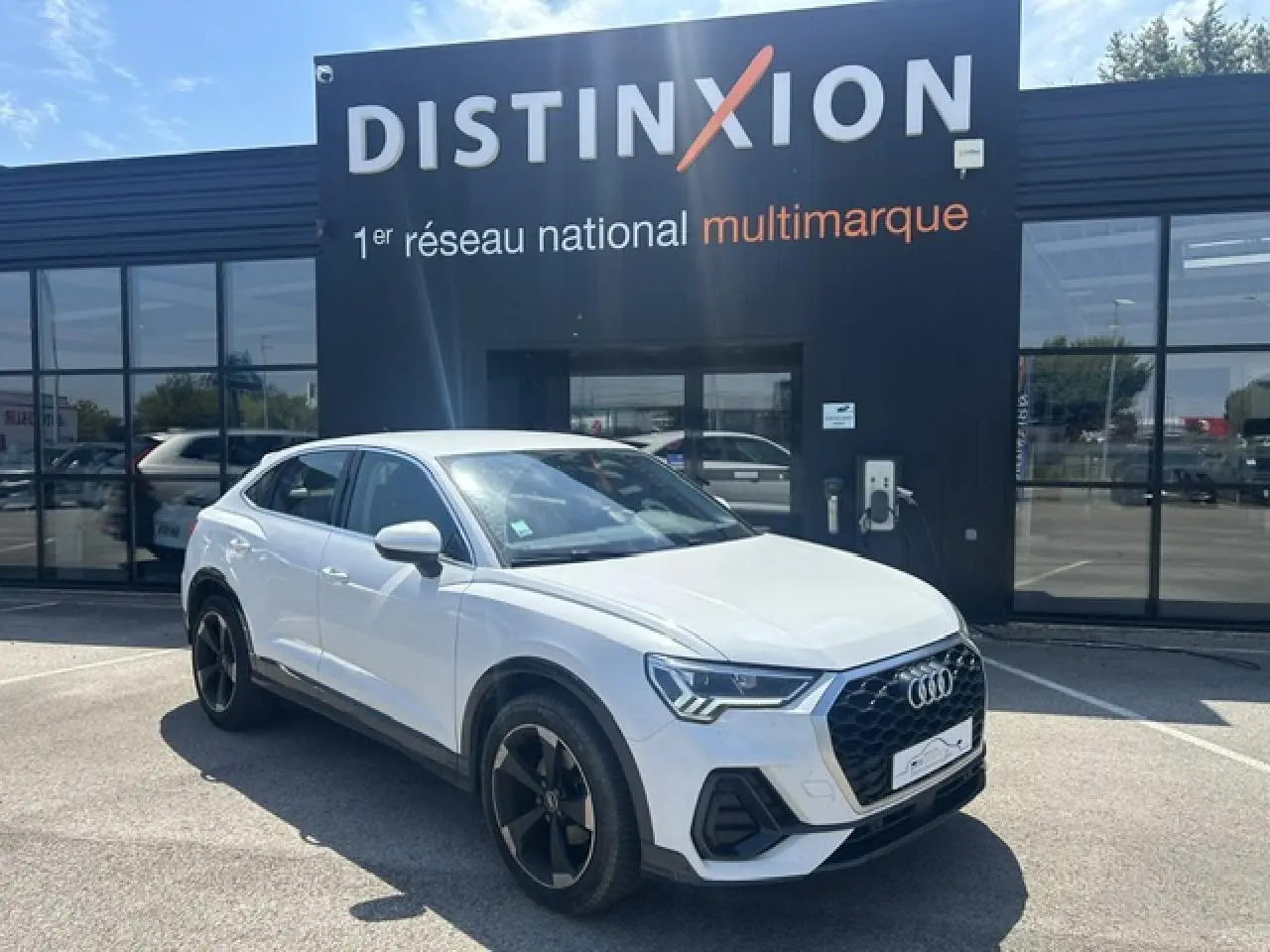 Audi Q3 Sportback blanc en 3/4 avant droit, avec calandre noire et jantes noires à 5 branches doubles.