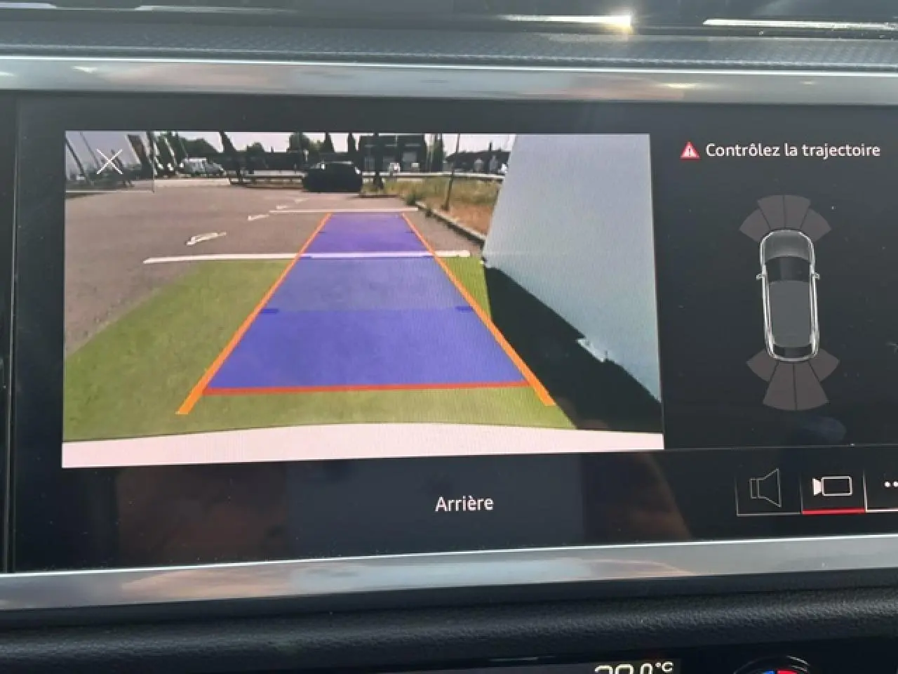 Vue de l'écran de caméra de recul de l'Audi Q3 blanc, affichant les lignes de guidage et l'alerte de trajectoire.