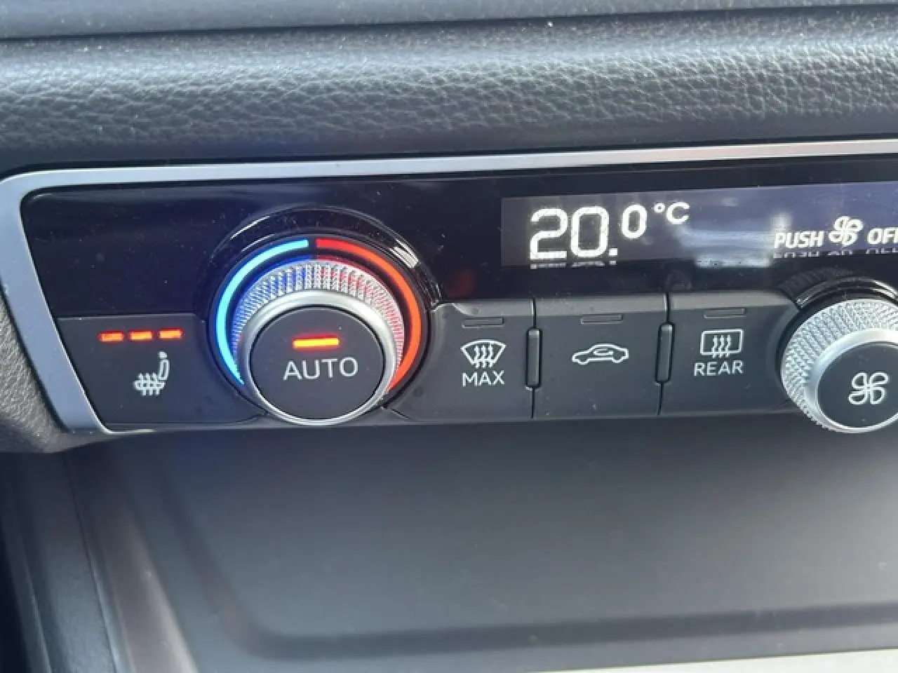 Gros plan sur la commande de climatisation automatique avec réglage à 20°C et siège chauffant activé, intérieur noir.