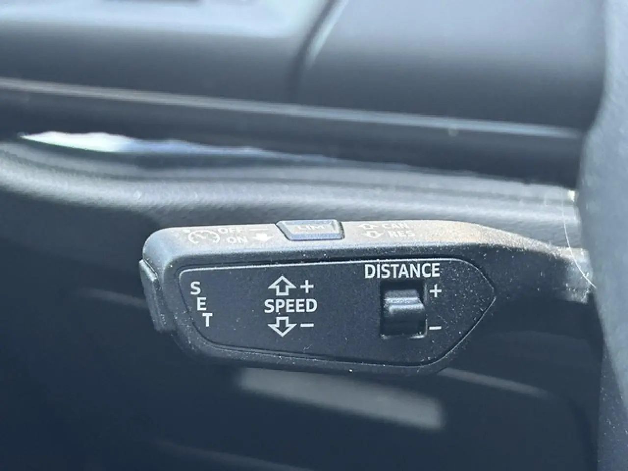 Gros plan sur la commande de régulateur de vitesse noire dans l’habitacle d’un Audi Q3 blanc de 2022.