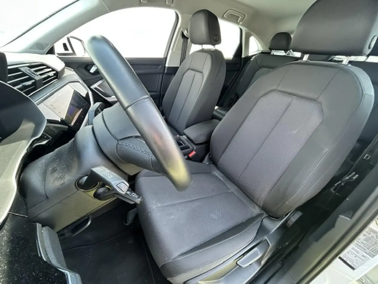 Vue intérieure côté conducteur de l'Audi Q3 Sportback 2022, sièges tissu gris et volant cuir noir.