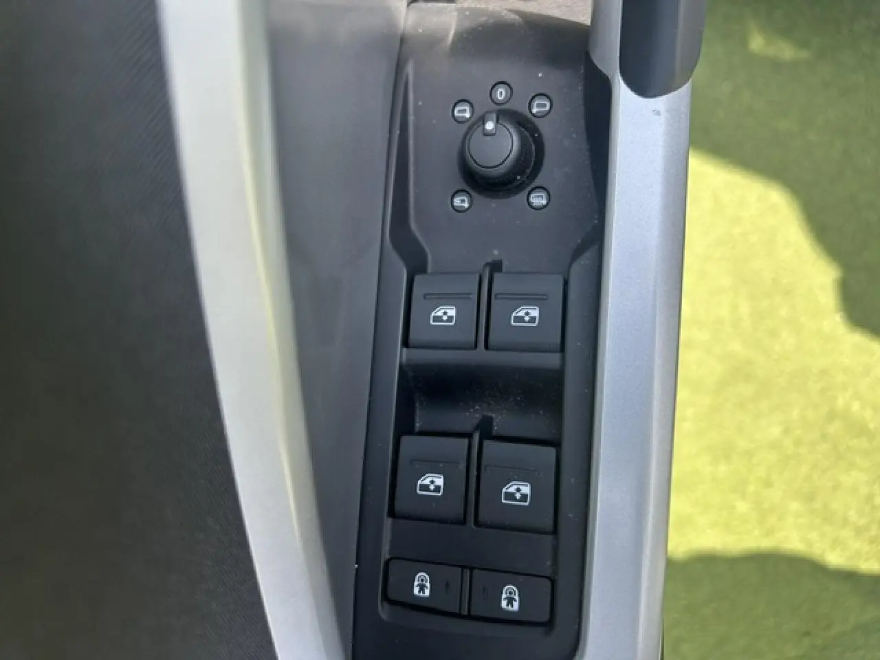 Gros plan sur les commandes des vitres et rétroviseurs côté conducteur d’un Audi Q3 blanc 2022.