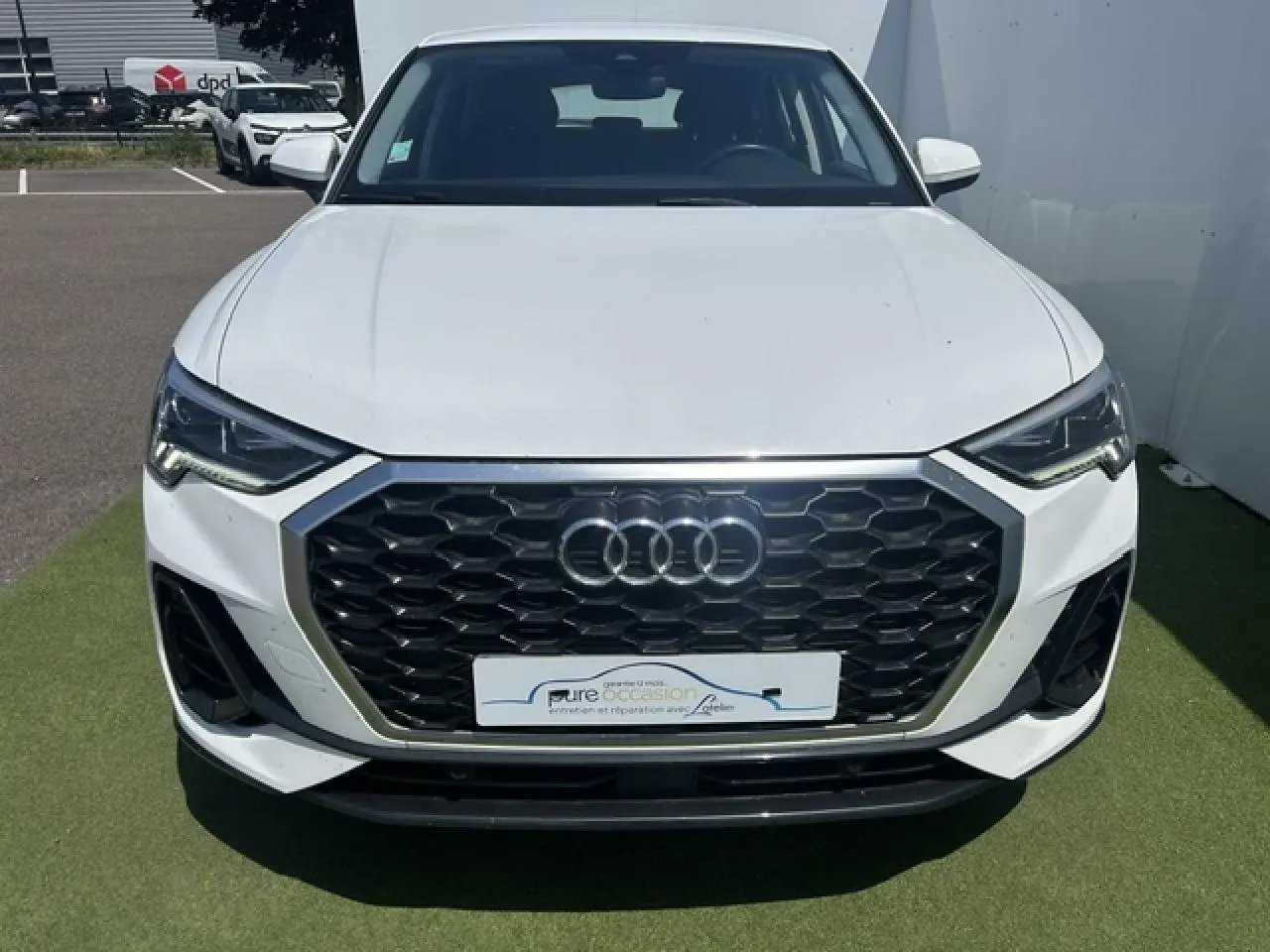 Vue avant d'un Audi Q3 blanc avec calandre noire hexagonale et phares LED distinctifs.