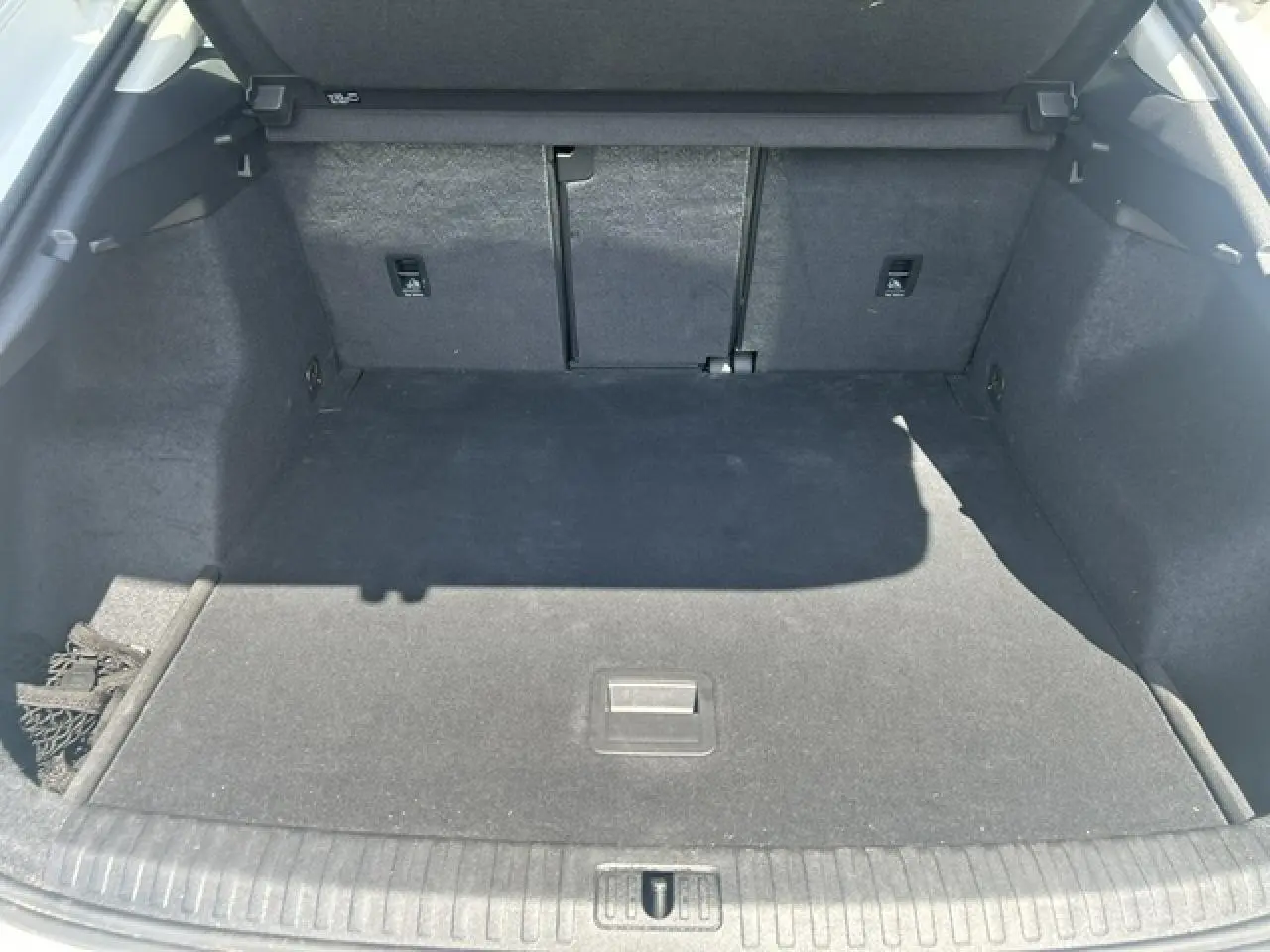 Coffre ouvert vu de l'arrière d'un Audi Q3 blanc, montrant un espace de chargement vide et tapis noir.