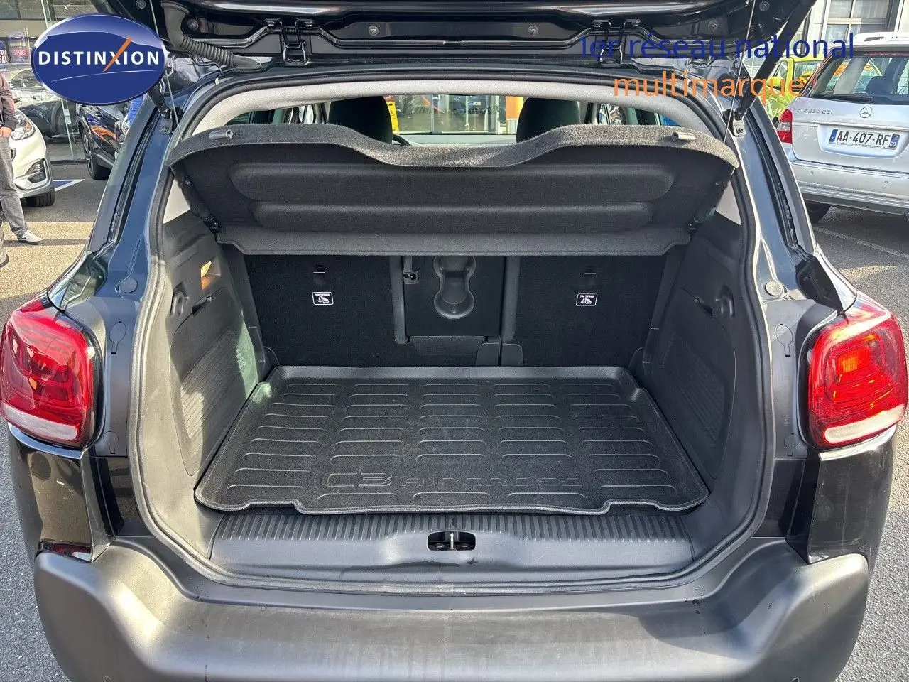 Coffre ouvert vu de l'arrière d'un Citroën C3 Aircross noir Perla Metal avec tapis de coffre marqué du modèle.