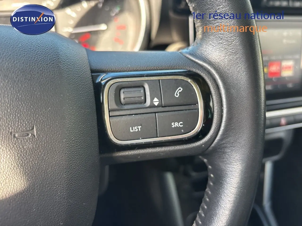 Gros plan sur les commandes gauche du volant en cuir noir du Citroën C3 Aircross 2019, intérieur moderne et écran tactile en arrière-plan.