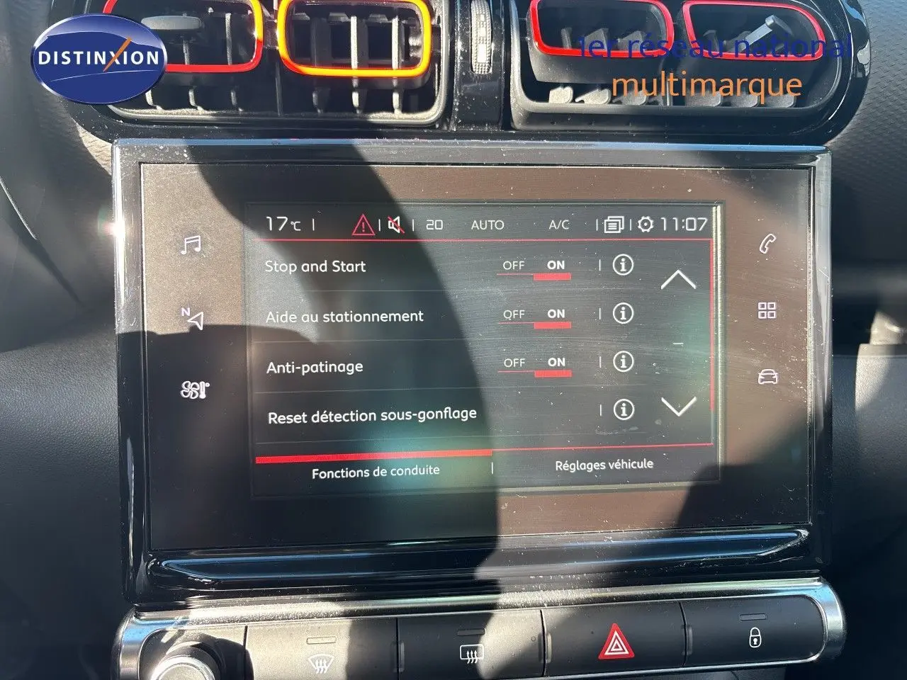Vue rapprochée de l’écran tactile central et des aérateurs colorés rouge et orange du tableau de bord d’une Citroën C3 Aircross noir perla metal.