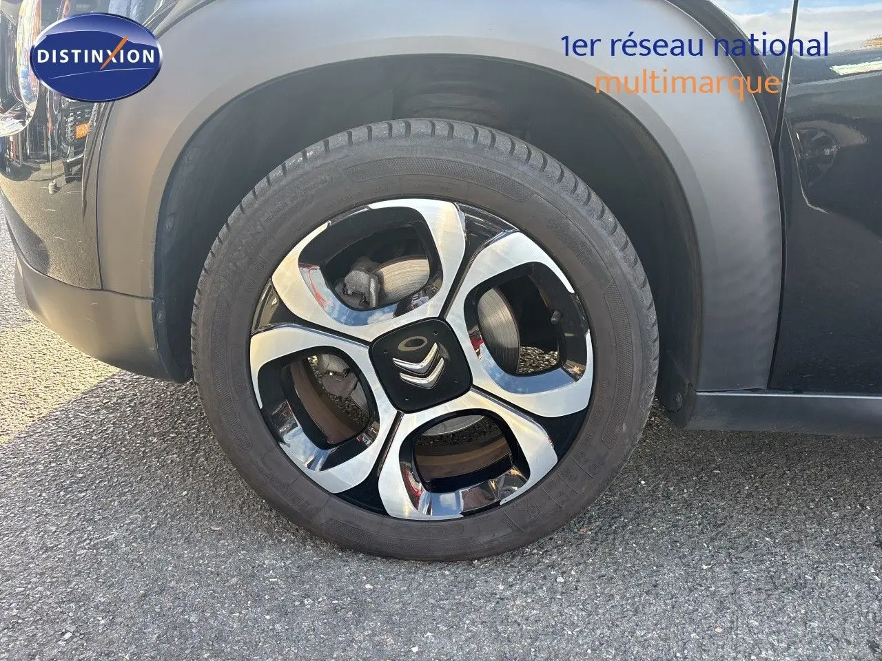 Gros plan sur la roue avant gauche d'une Citroën C3 Aircross noir perla metal avec jante alliage bicolore distinctive.