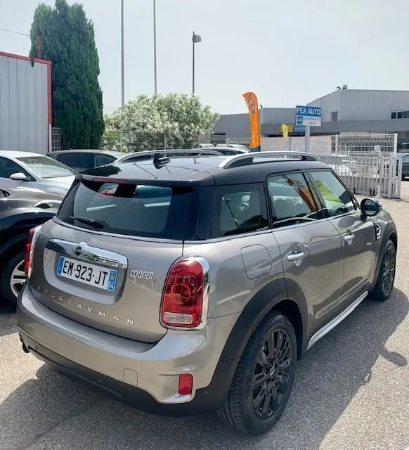 Vue 3/4 arrière droite d'une MINI Countryman Cooper D 150ch gris avec toit noir et jantes noires, stationnée en extérieur.