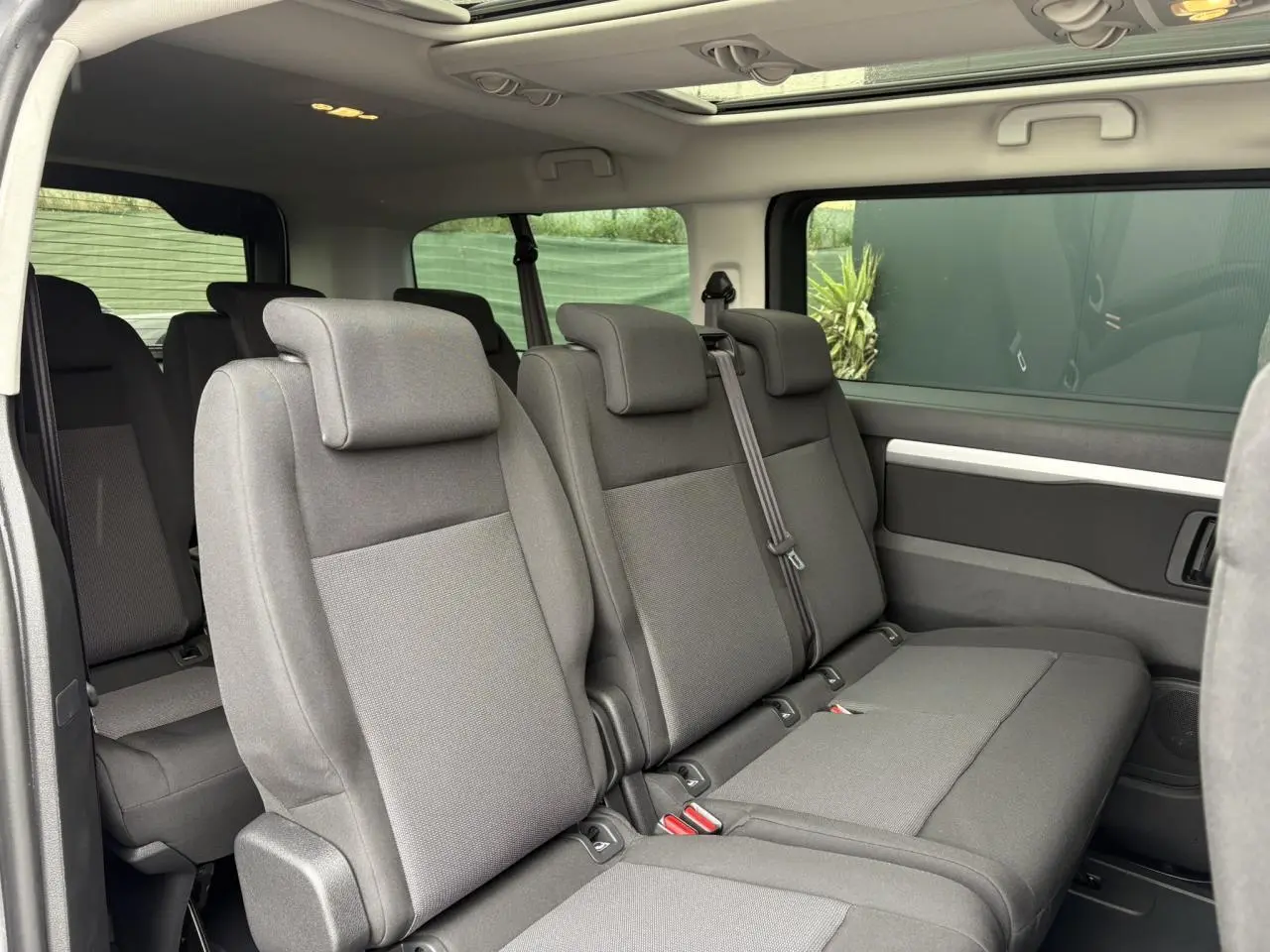 Vue intérieure côté droit des sièges arrière gris du Opel Zafira Life XL avec toit panoramique visible au plafond