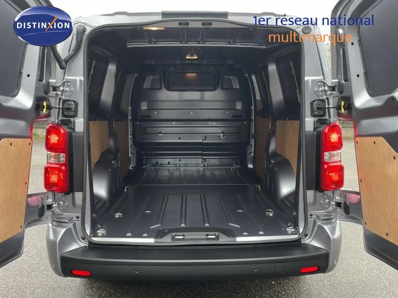 Vue arrière du Citroën Jumpy gris Artense avec portes ouvertes montrant l’espace de chargement vide et les feux arrière allumés.