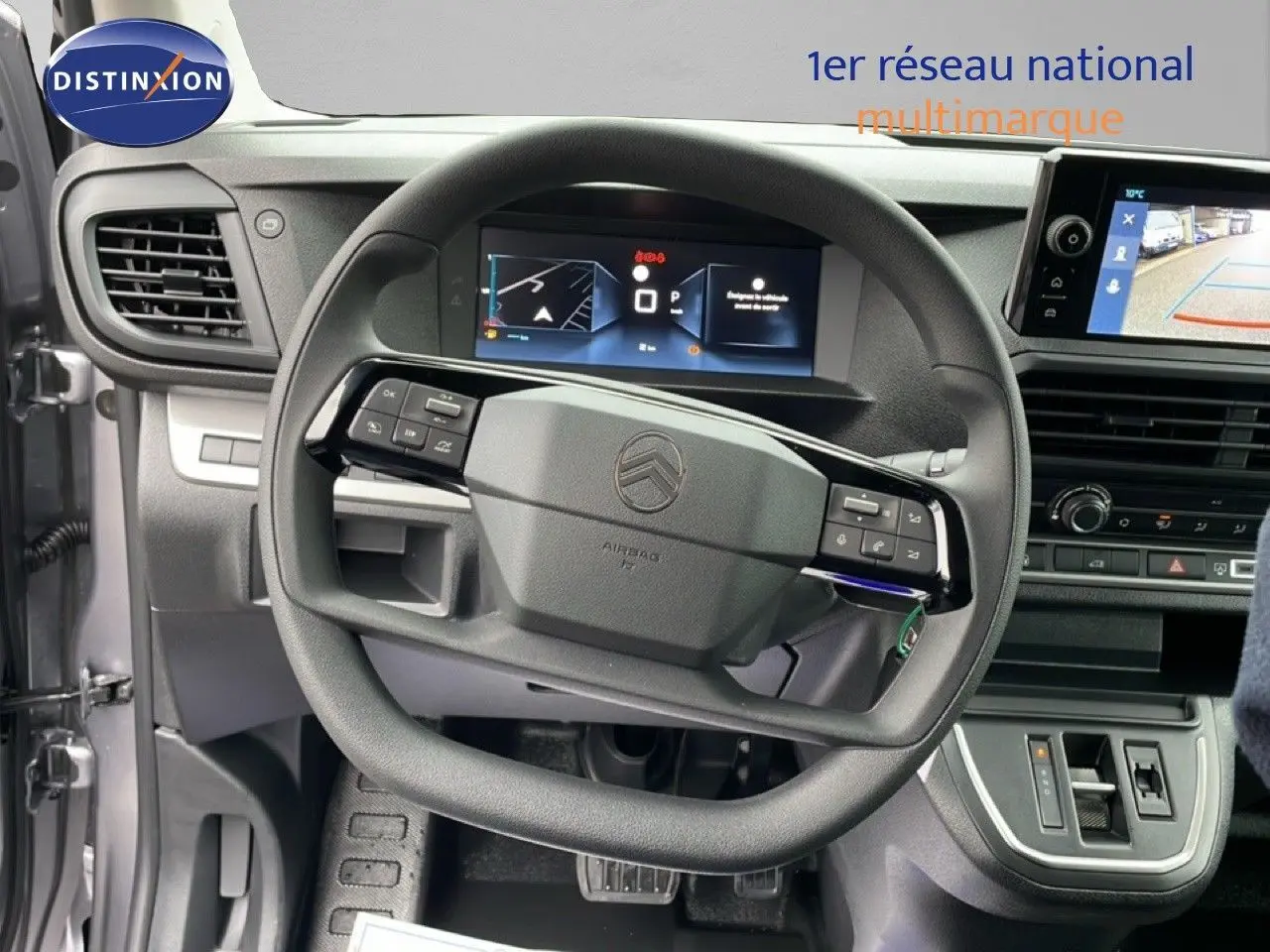 Vue intérieure centrée sur le volant et tableau de bord du Citroën Jumpy gris, avec écran tactile et affichage numérique.