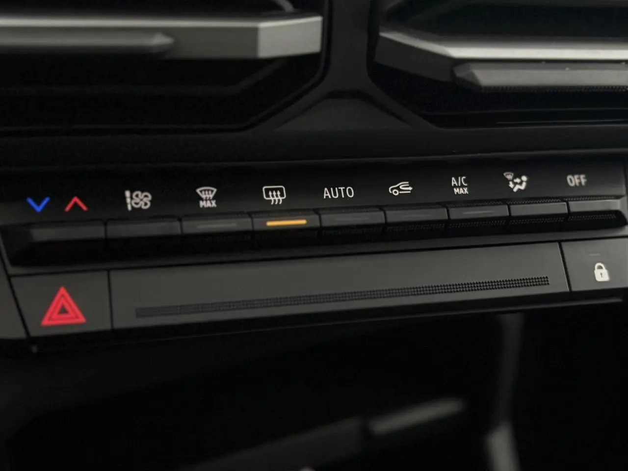 Gros plan sur la console centrale du Dacia Duster 2026, montrant les commandes de climatisation et d’alerte en noir.