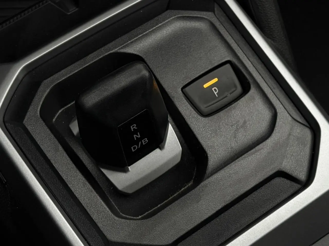 Gros plan sur le levier de vitesses automatique et bouton de stationnement électrique du Dacia Duster gris Schiste.