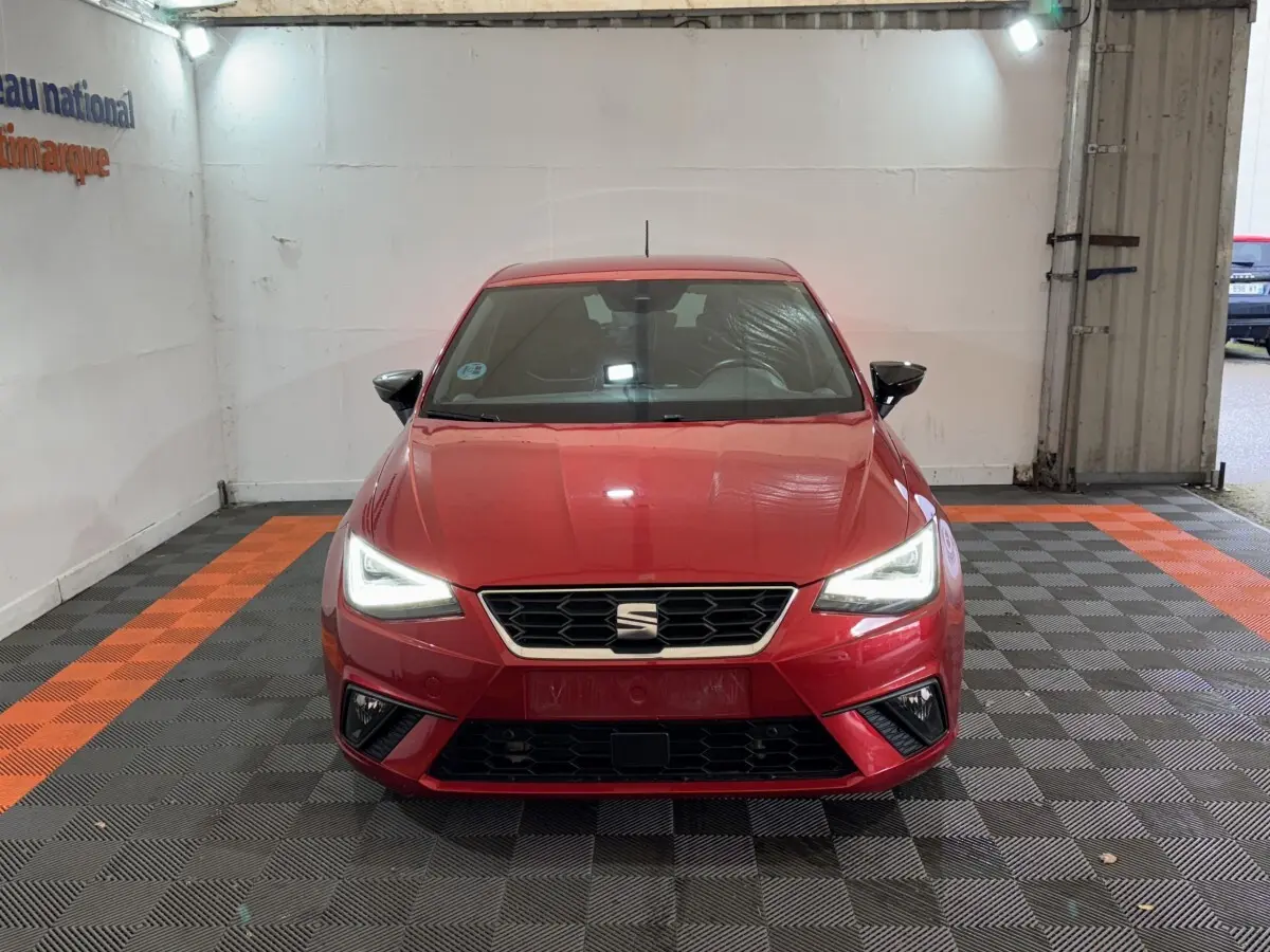Vue frontale d'une SEAT Ibiza rouge 2024 avec phares LED allumés dans un garage éclairé.
